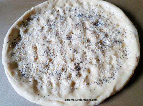 Stretch the dough into large uneven rounds and indent the dough with your fingertips.